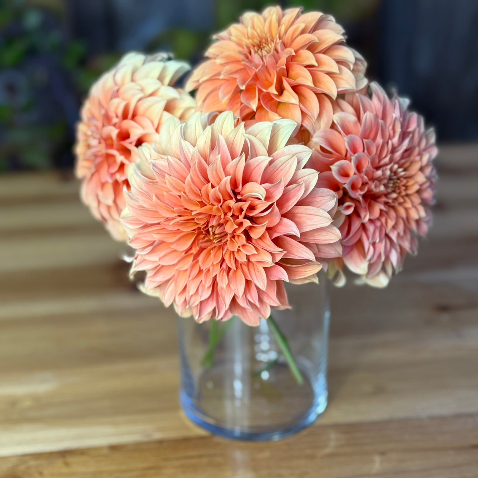 Clear glass vase with peach-colored flowers on a wooden surface