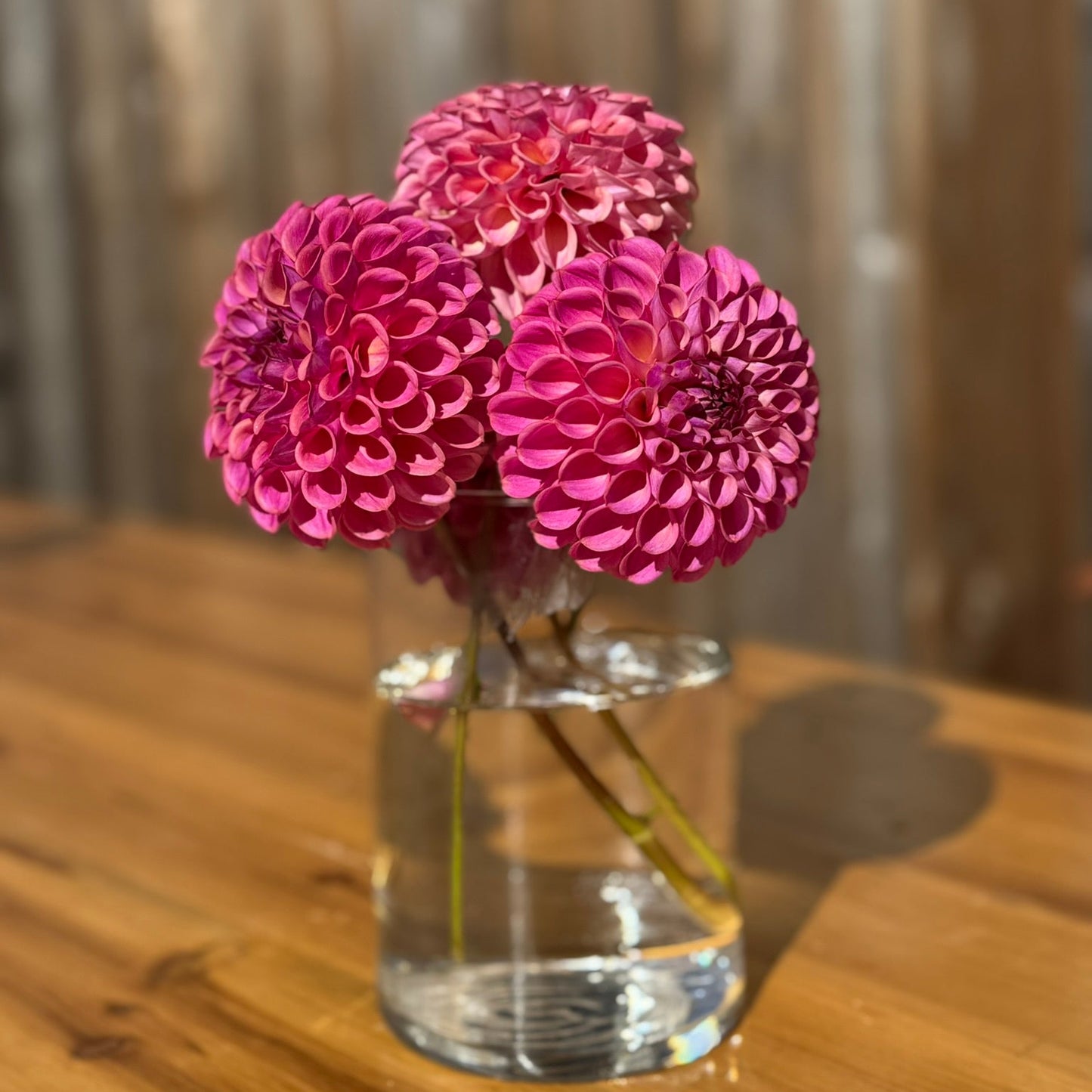 Clear vase with pink flowers on a wooden table