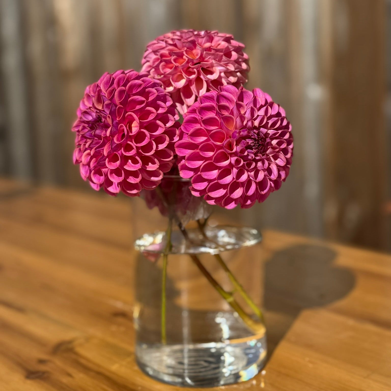 Clear vase with pink flowers on a wooden table