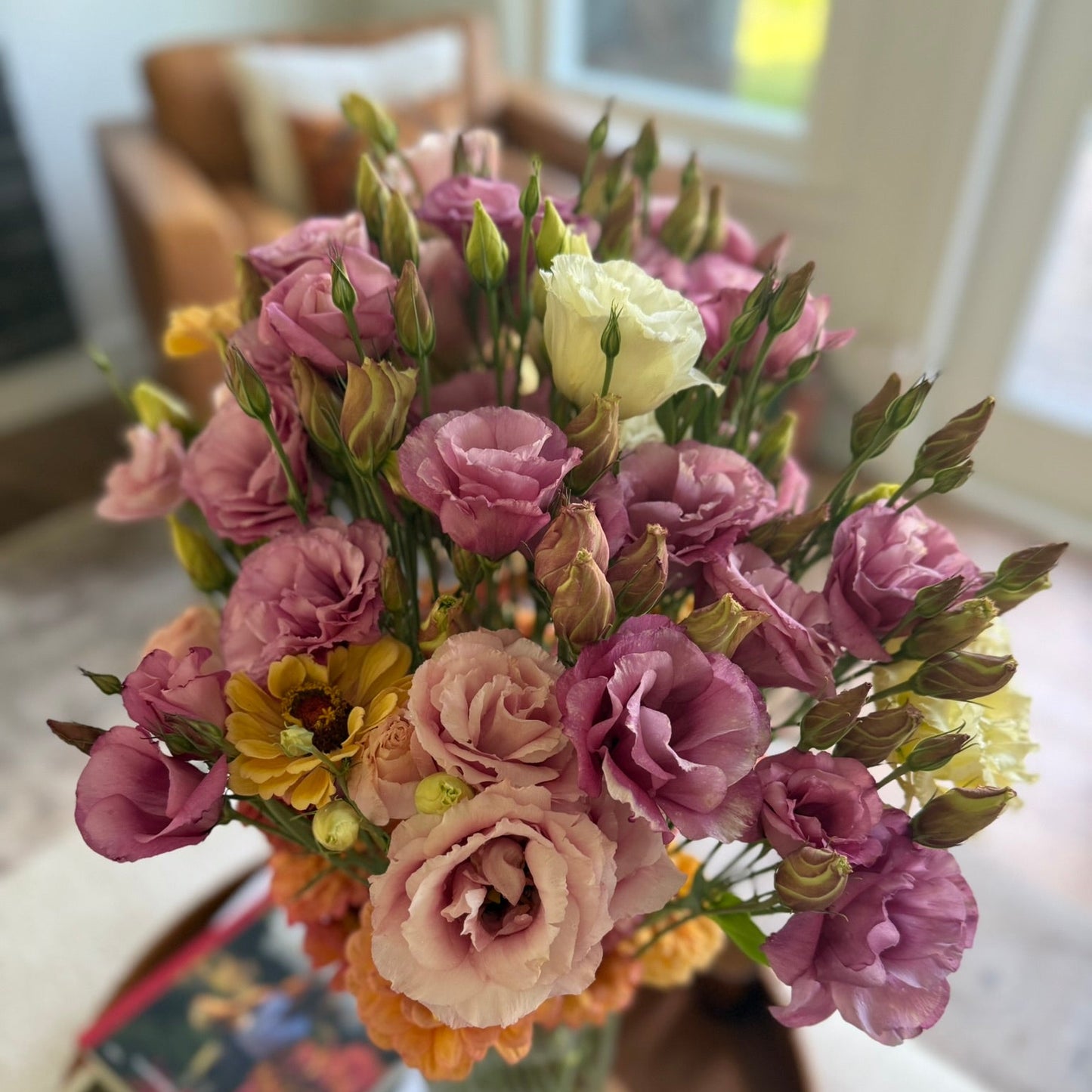 Bouquet of flowers in a vase on a table with books in the background