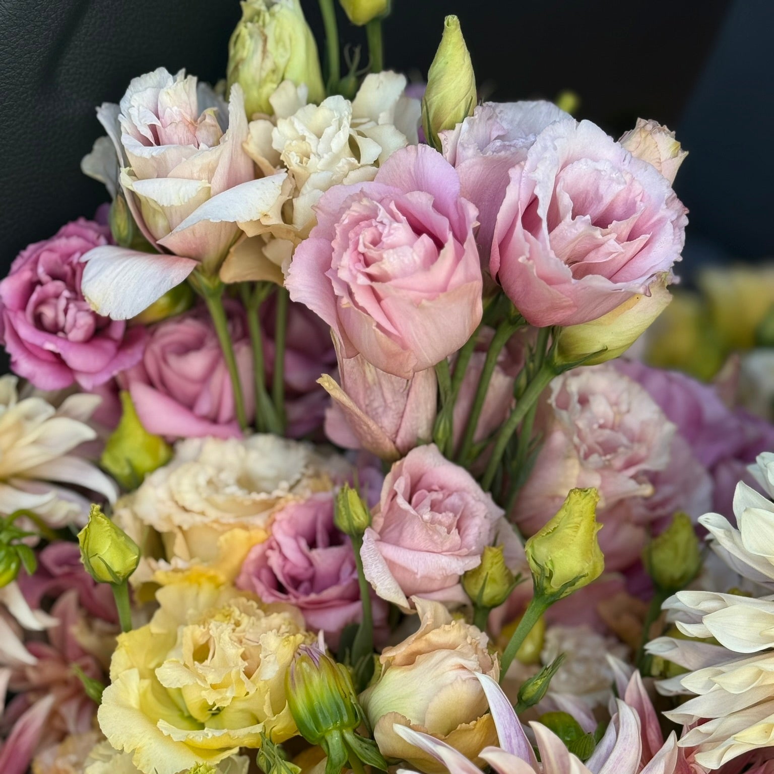 Bouquet of pink, yellow, and white flowers with green stems.