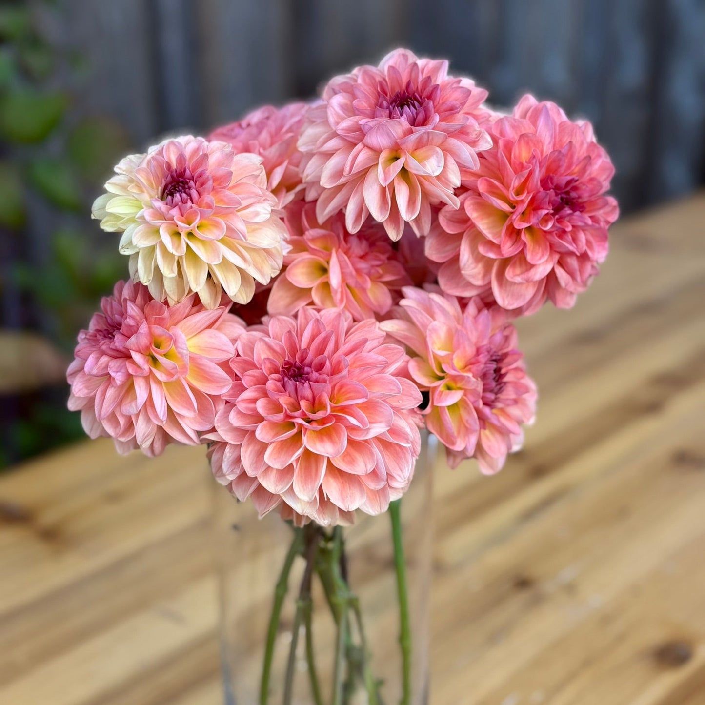 Bouquet of pink and yellow flowers in a clear vase on a wooden table