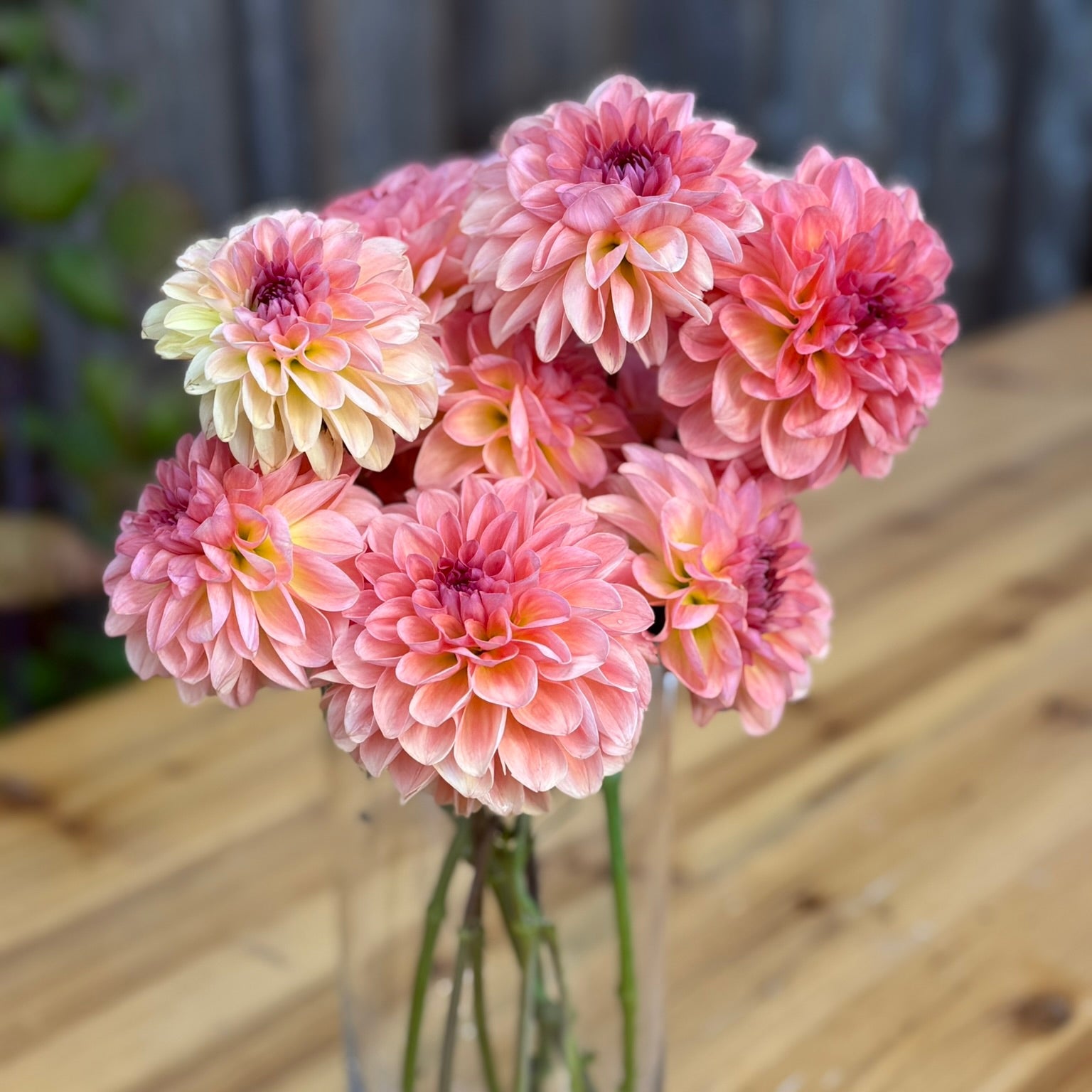 Bouquet of pink and yellow flowers in a clear vase on a wooden table
