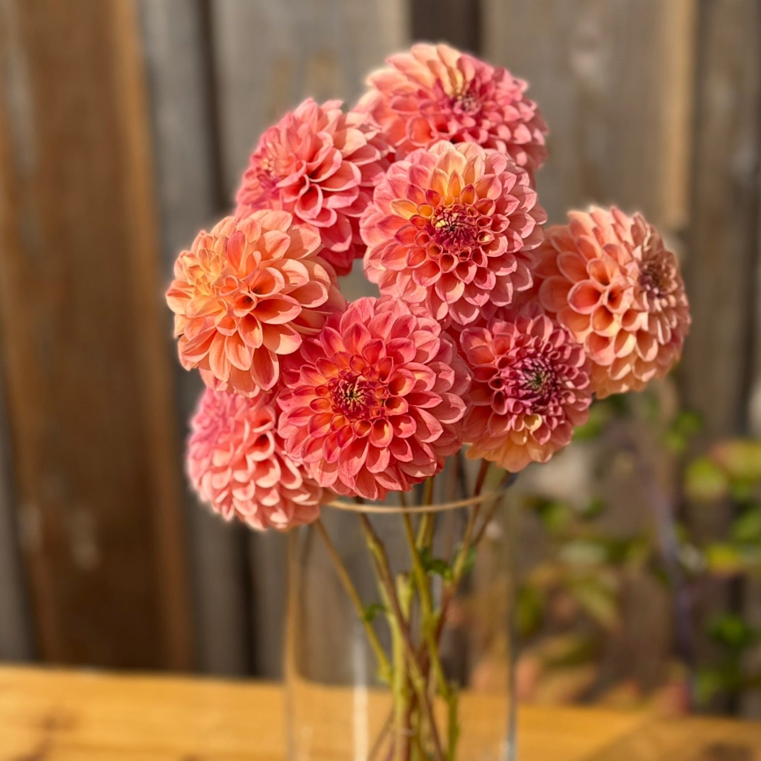 Clear glass vase with pink flowers on a wooden surface